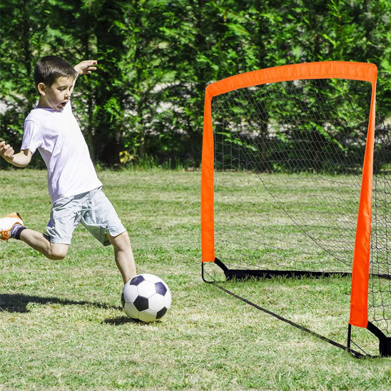 garson tire un ballon dans la cage de foot