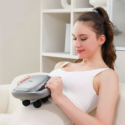 Une Femme assise utilisant un pistolet de massage sur son son abdomen.