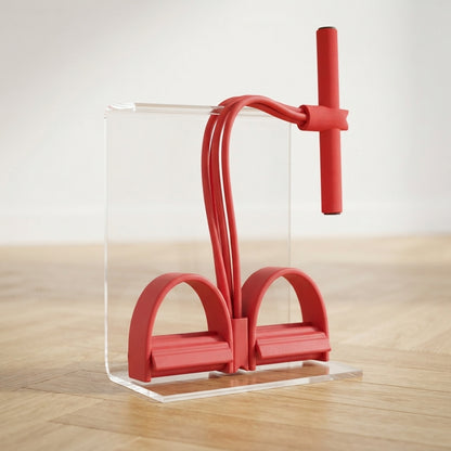 Élastique musculation rouge avec pédales posé sur présentoir en plexiglas.