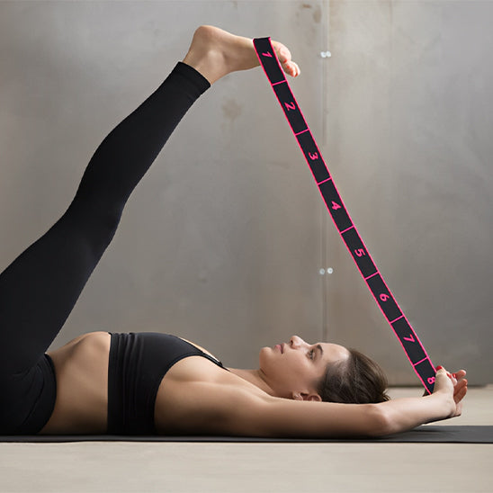 Femme allongée étire jambes avec élastique musculation sur tapis noir.