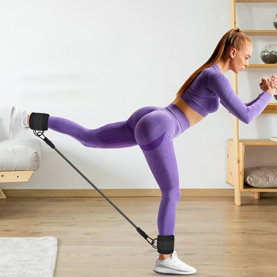 Femme faisant un kickback avec un élastique musculation aux chevilles.