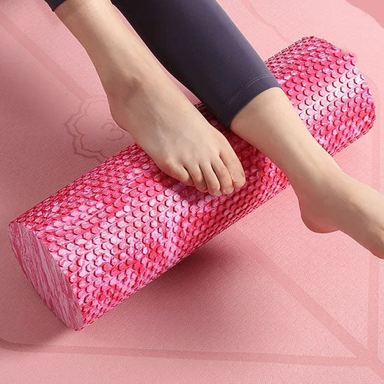 Pied sur un rouleau de massage, sur tapis d’exercice rose.