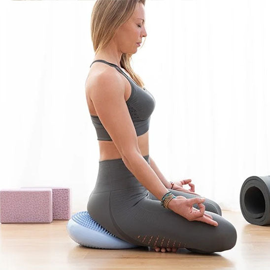 Une Femme assise  méditant sur tapis pilates, posture zen, concentrée.
