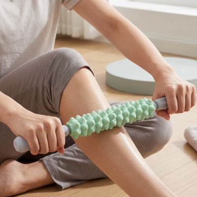Une femme masse sa jambe avec un rouleau de massage.
