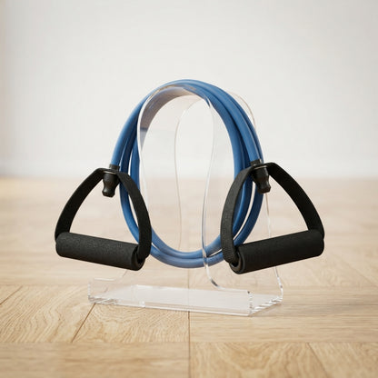 Élastique musculation bleu avec poignées sur support transparent parquet bois.