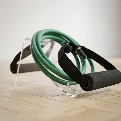 Élastique musculation vert sur présentoir transparent avec poignées noires visibles.