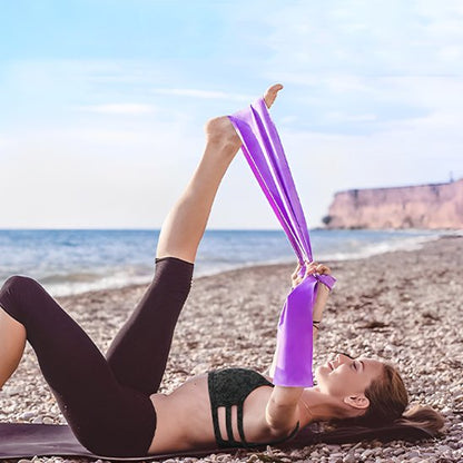 Élastique musculation violet femme étire jambe allongée sur sable, plage.