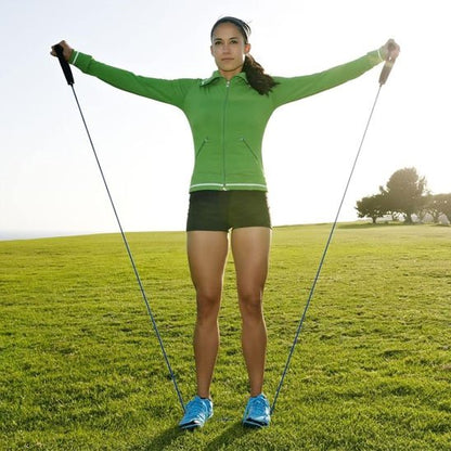 Femme étire élastique musculation en extérieur bras levés au soleil.