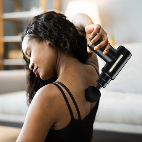 femme utilise avec pistolet de massage sur le haut de son dos