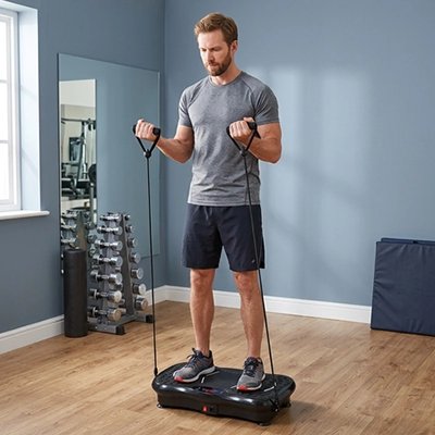 Homme utilisant plateforme vibrante avec poignées, entraînement en salle.