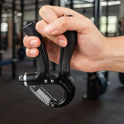 Main serrant un hand grip dans une salle de sport.