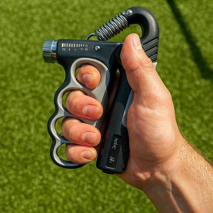 Main serrant un hand grip en extérieur sur fond vert.