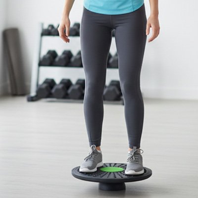 Personne debout sur planche d’équilibre en  salle de sport.