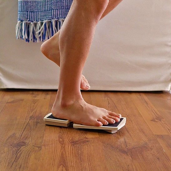 Personne utilisant une planche d'équilibre en bois sur parquet.