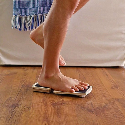 Personne utilisant une planche d'équilibre en bois sur parquet.