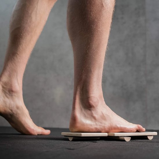 Pieds d'un homme s'exerçant sur planche d'équilibre.