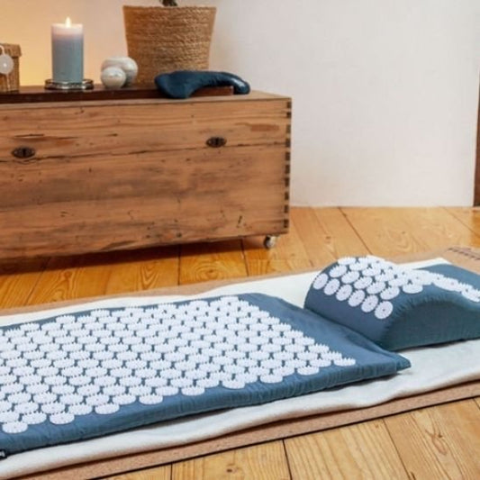 Tapis d acupression et oreiller posé sur sol en bois.