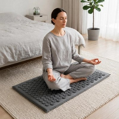 Tapis d acupression gris, femme méditant en tailleur, chambre calme.