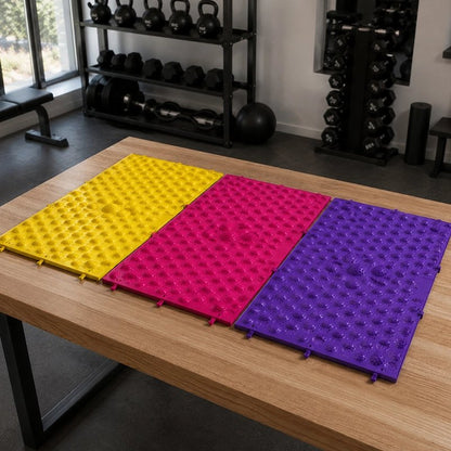 Trois tapis d'acupression colorés sur table, salle de musculation.