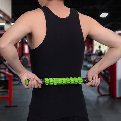 Un Homme massant son dos avec un rouleau de massage  dans salle de sport.