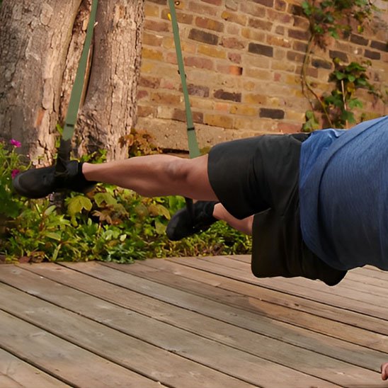 Un homme réalise un gainage suspendu utilisant une sangle musculation.