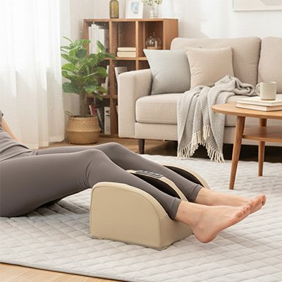 Une femme allongée sur tapis masse ses mollets avec  appareil masseur pieds