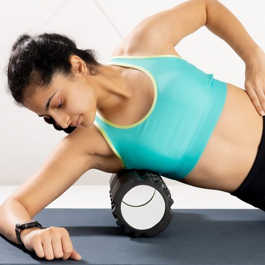 Une femme allongée utilise un rouleau de massage aux côte.