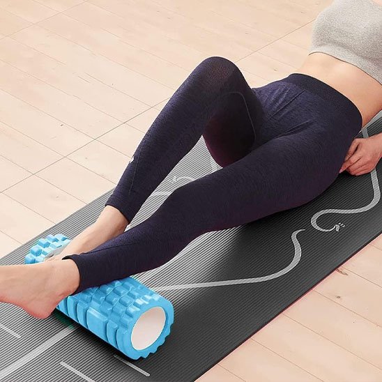 Une femme allongée utilise un rouleau de massage aux mollets et pied