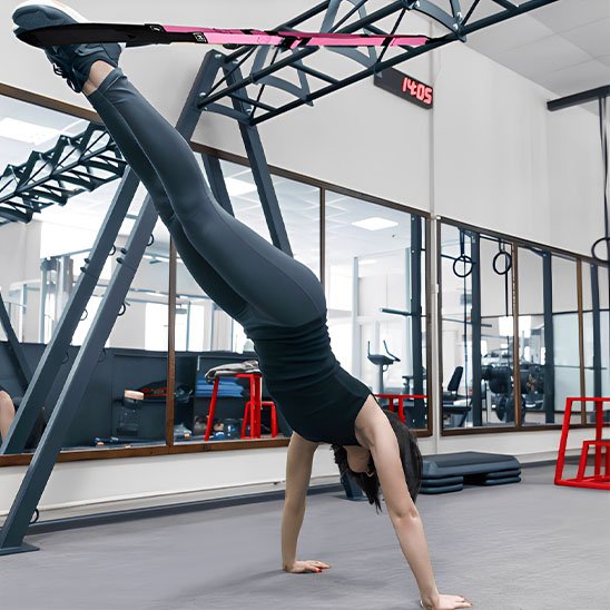 Une Femme fait handstand avec Sangle musculation salle de sport.