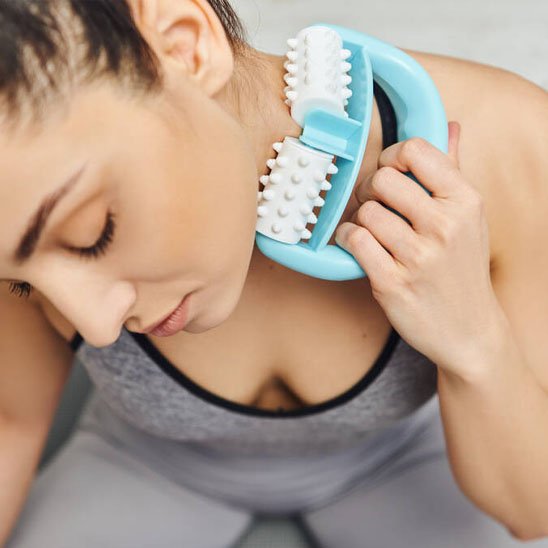 Une femme masse son cou avec un rouleau de massage.