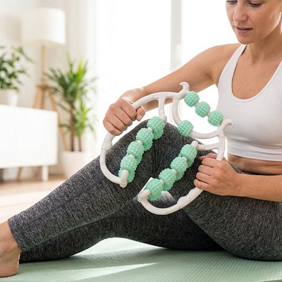 Une Femme utilisant un rouleau de massage sur sa cuisse.