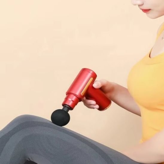 une femme utilise un pistolet de massage rouge sur la jambe