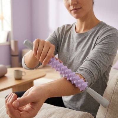 Une femme utilise un rouleau de massage sur son avant-bras.