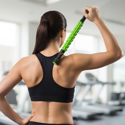 Une Femme vue de dos massant son trapèze avec un rouleau de massage.