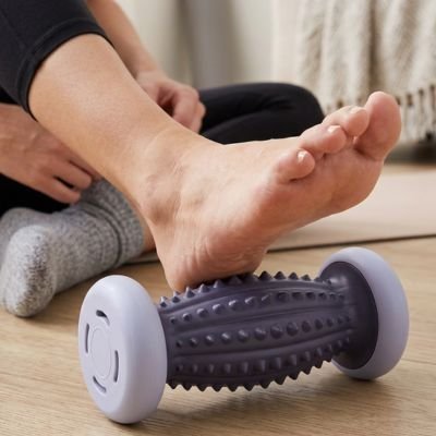 Une personne assise au sol utilise un rouleau de massage.